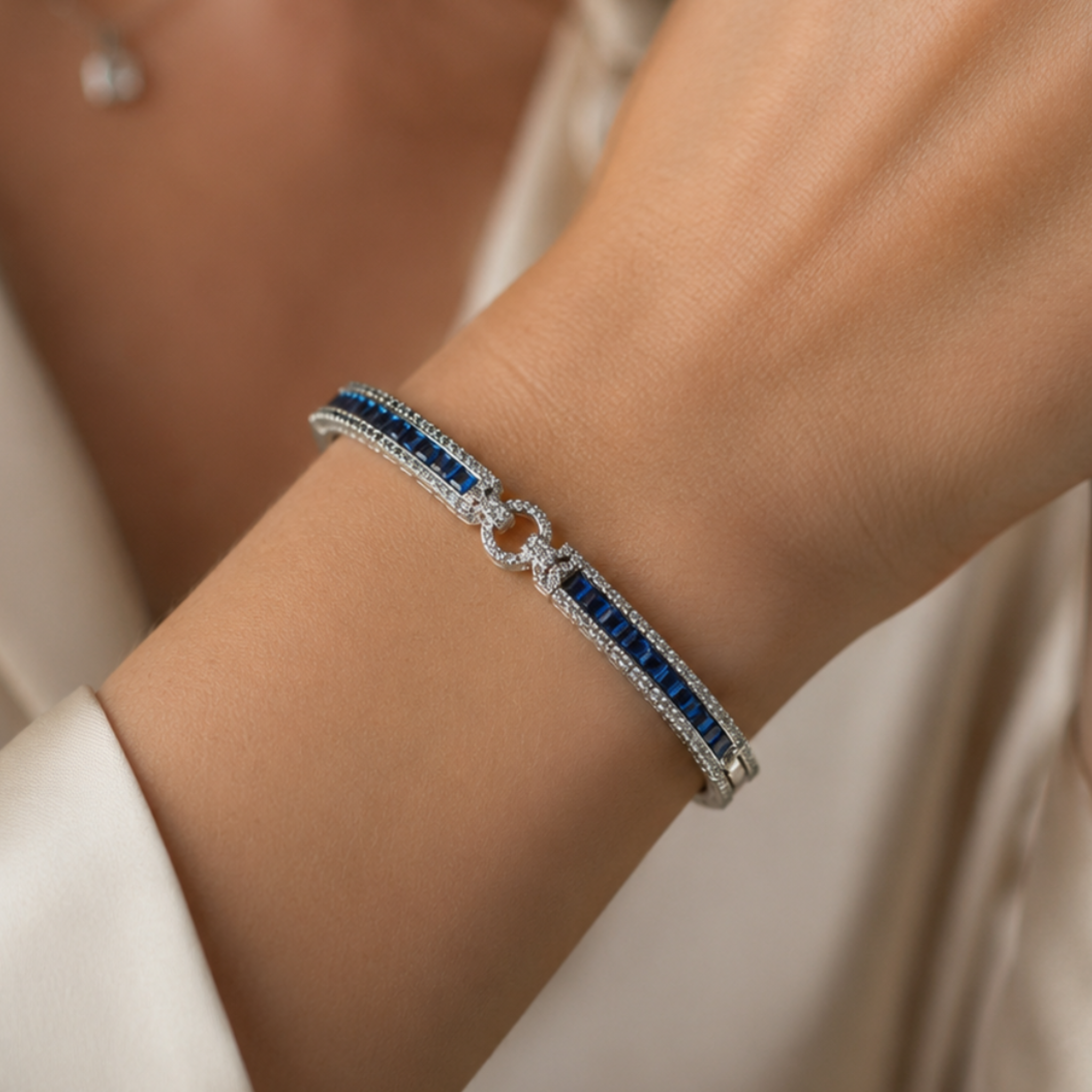 A close-up of a silver-toned bracelet with a row of deep blue rectangular stones and a central openwork circle motif, worn on a person's wrist.