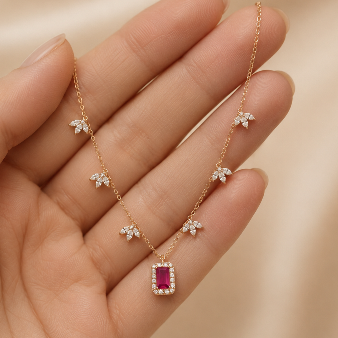 A delicate rose gold necklace with a rectangular pink gemstone pendant and five small star-shaped crystal clusters along the chain, displayed on a hand.