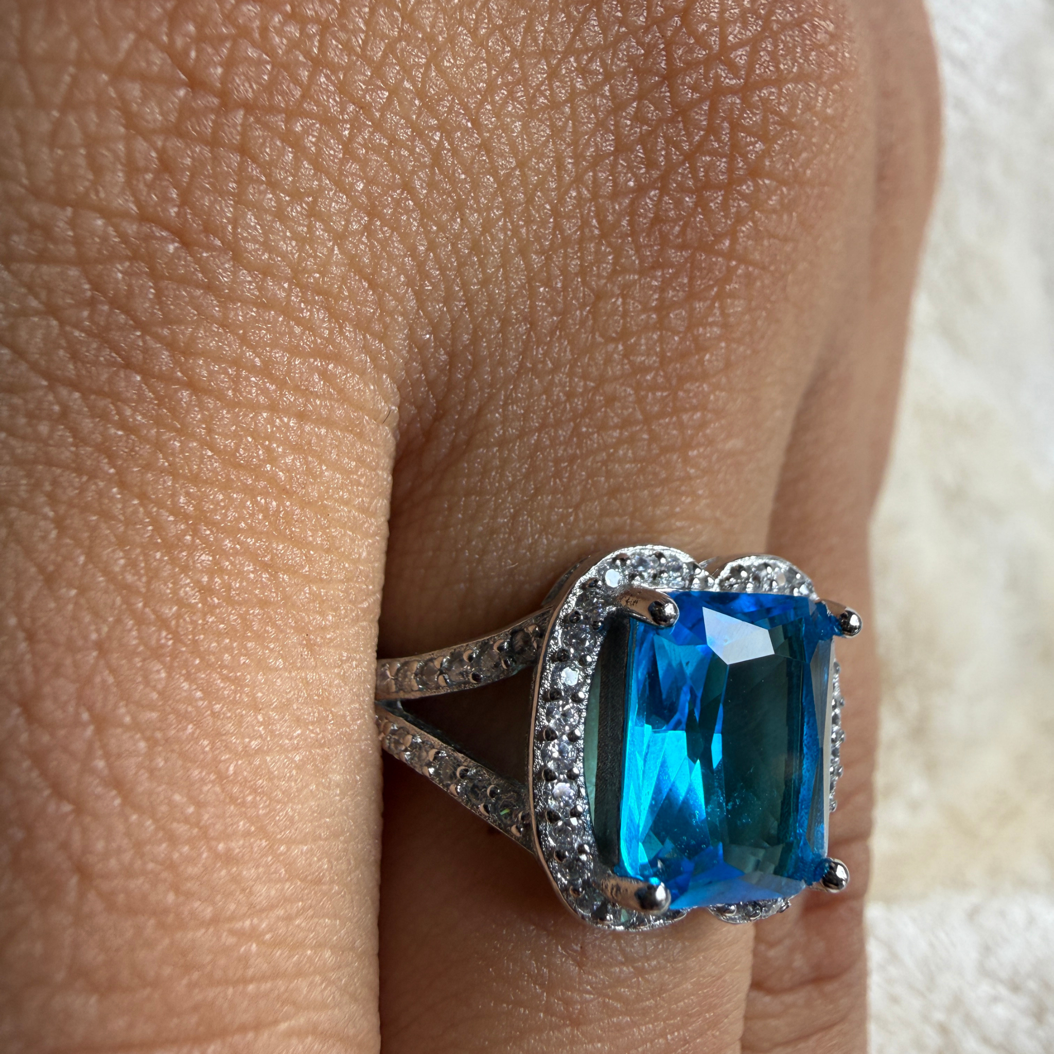 Blue emerald-cut gemstone and lab-grown diamond halo ring by Kiashaa Jewellery.