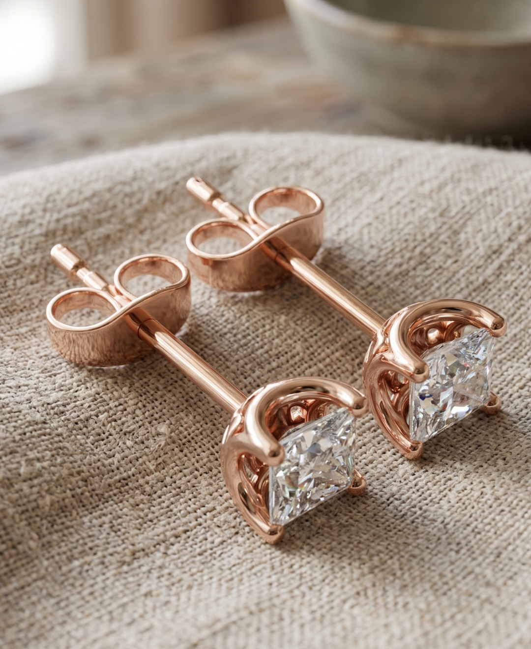 Close-up of princess cut lab-grown diamond earrings with polished four-prong basket setting.