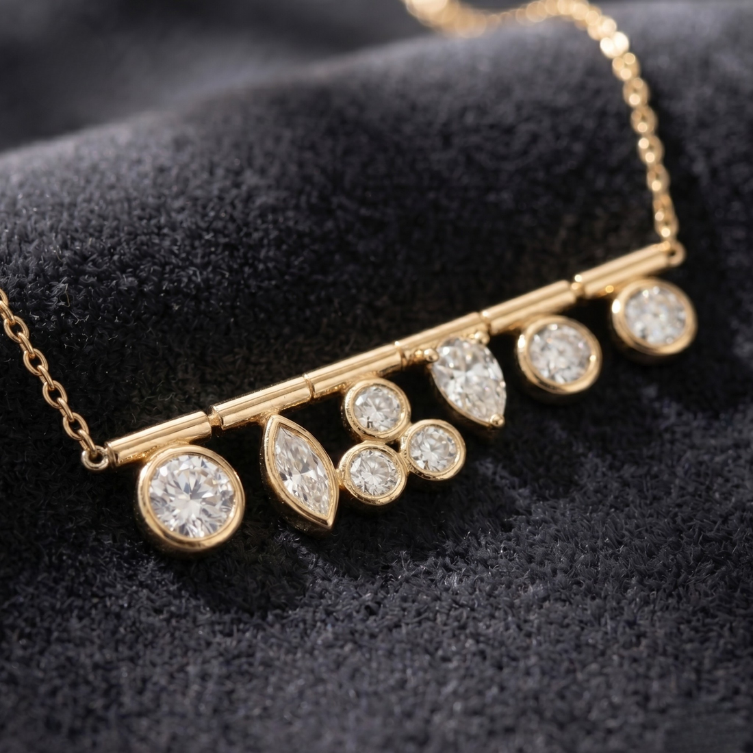 A gold bar necklace with multiple clear gemstones in round, marquise, and cluster settings, displayed on a textured black velvet surface.