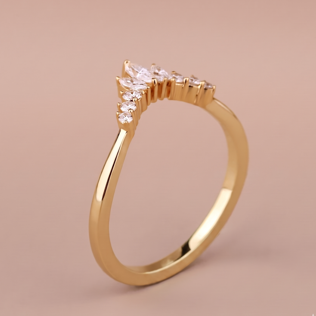 A gold ring with a marquise-cut center stone and smaller side stones, shown on a soft beige background.
