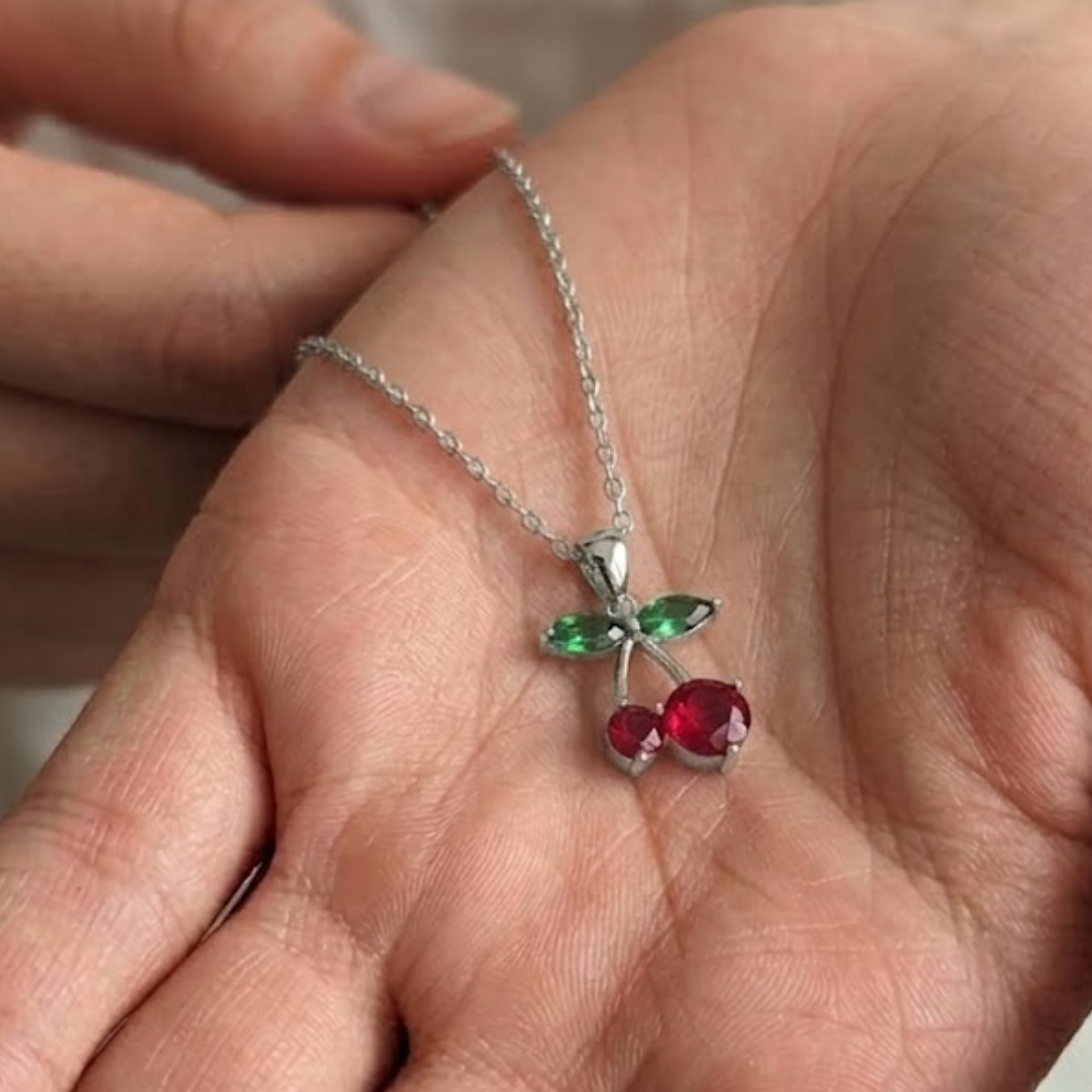 Fine jewelry necklace featuring two 1.50 by 3.00 millimeter green diamonds and two red gemstones.
