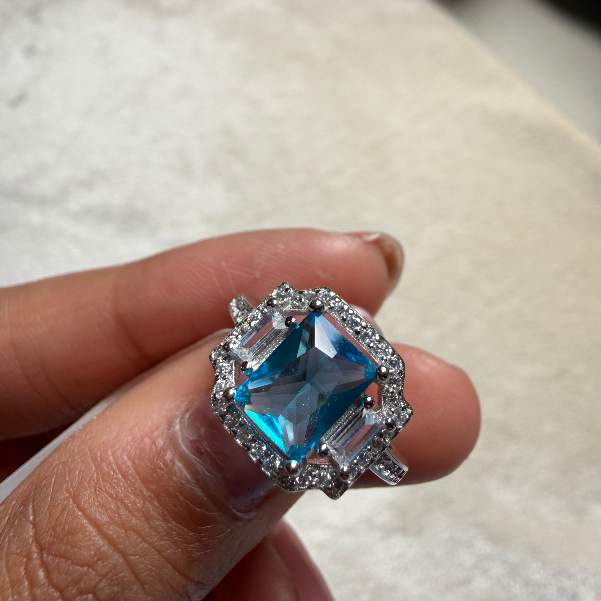 Blue emerald-cut gemstone and lab-grown diamond halo ring by Kiashaa Jewellery.