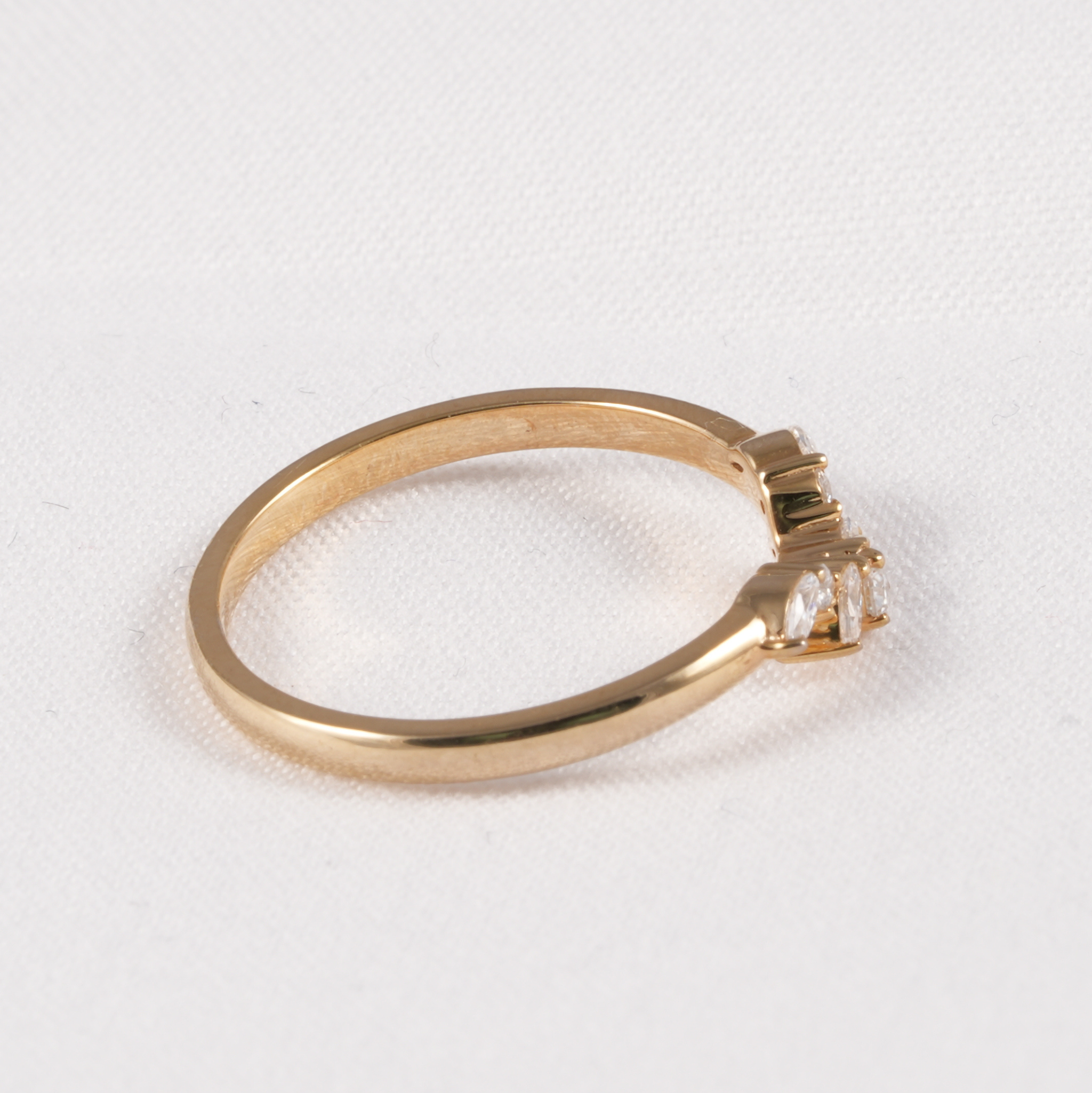 A yellow gold ring with a three-stone setting featuring clear rectangular gemstones, photographed on a textured white background.