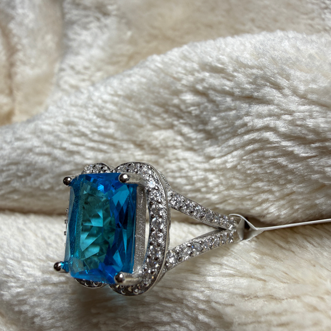 Blue emerald-cut gemstone and lab-grown diamond halo ring by Kiashaa Jewellery.