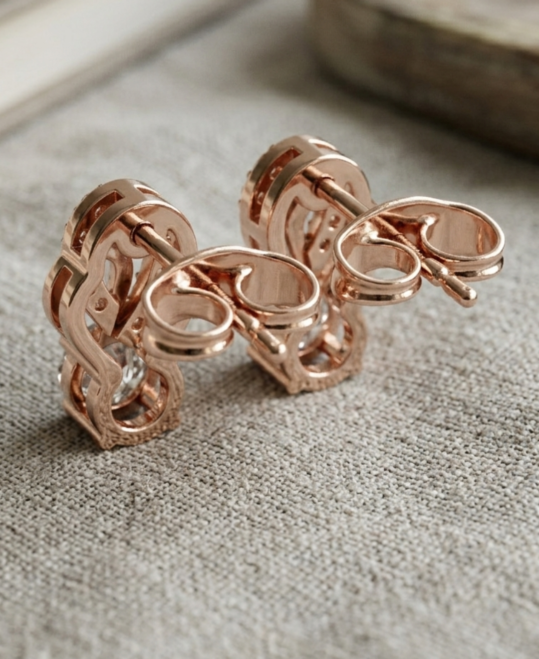Close-up of round diamond studs with sparkling pavé accents and an open teardrop design.