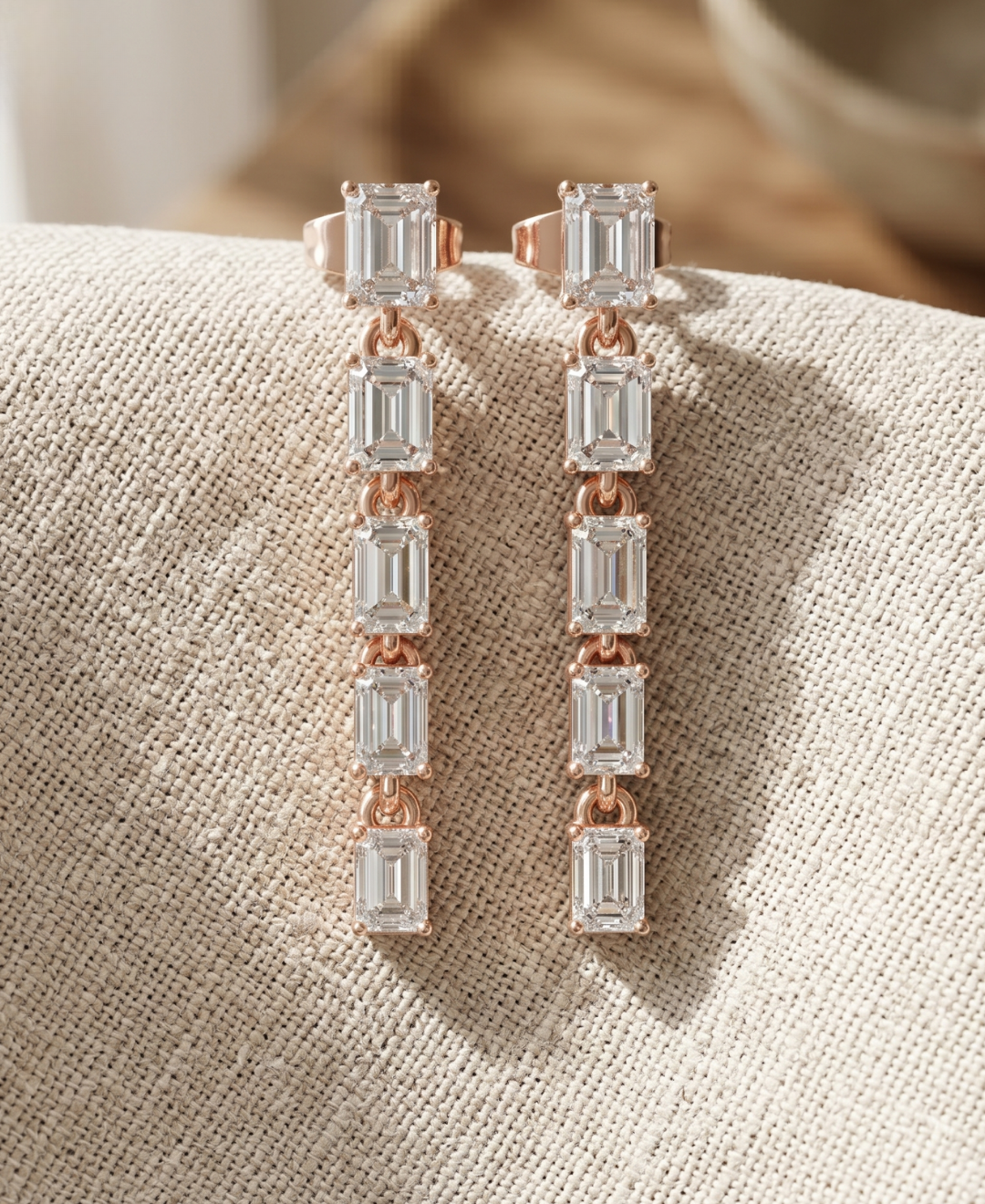 Close-up of emerald lab-grown diamond drop earrings by Kiashaa Jewellery with polished rose gold settings.