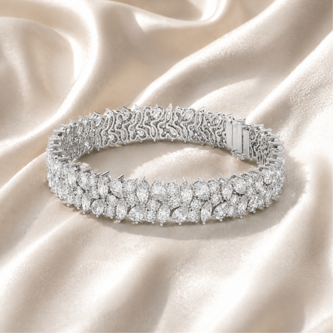 A diamond tennis bracelet with a textured pavé band and a central rectangular baguette accent, displayed on draped champagne satin fabric.