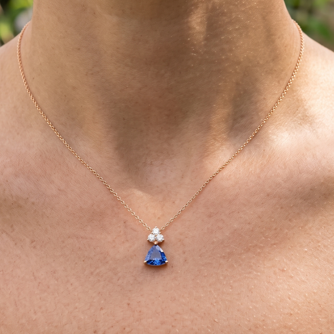 0.96 CTW blue trillion pendant necklace with a 6 mm center stone and three round diamond accents.