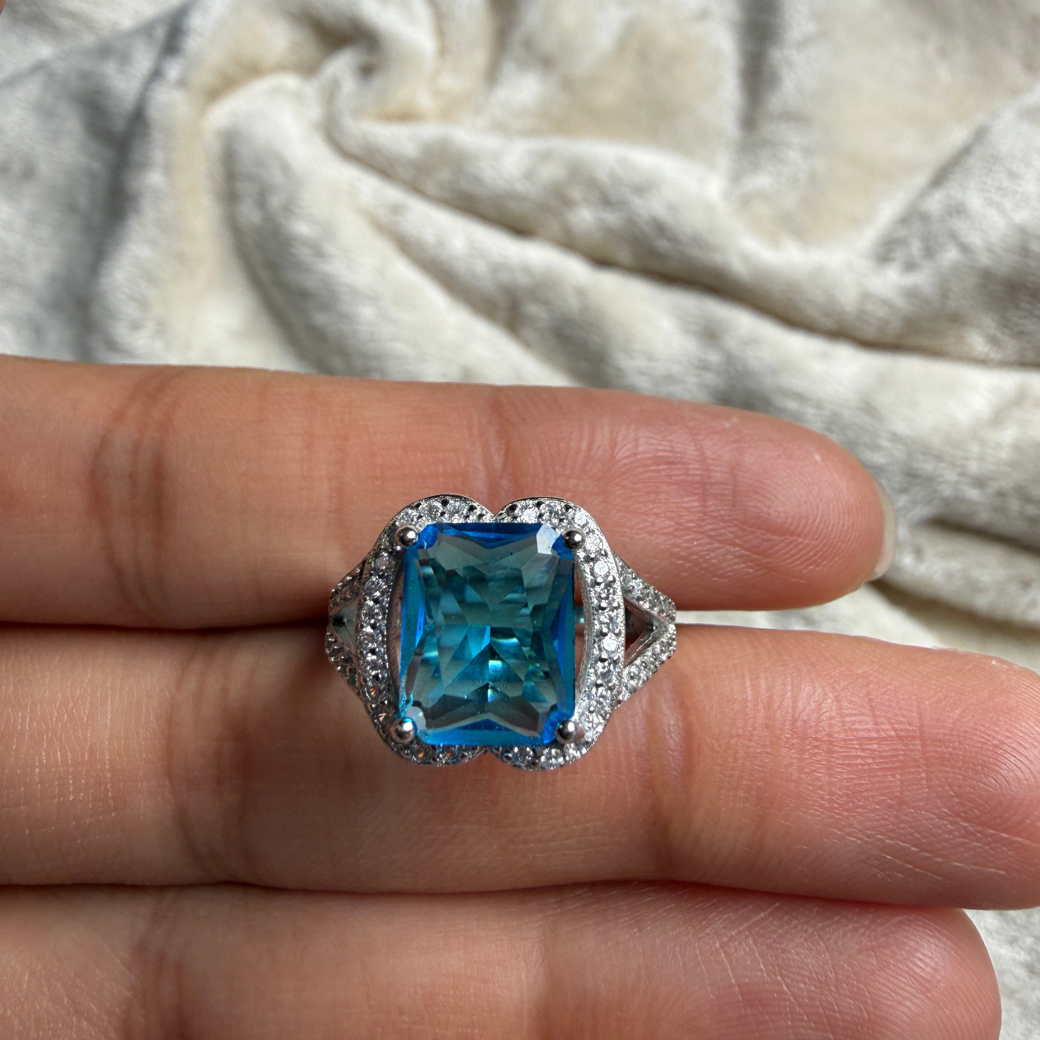 Blue emerald-cut gemstone and lab-grown diamond halo ring by Kiashaa Jewellery.