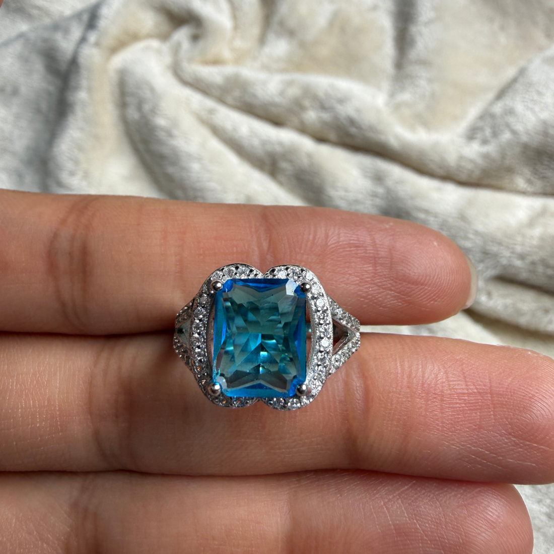 Blue emerald-cut gemstone and lab-grown diamond halo ring by Kiashaa Jewellery.