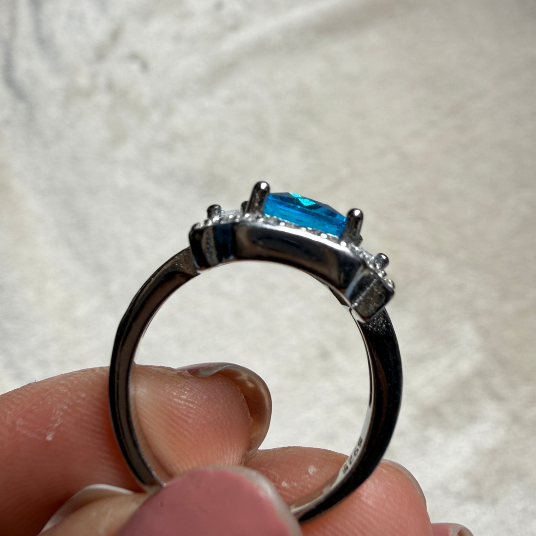 Blue emerald-cut gemstone and lab-grown diamond halo ring by Kiashaa Jewellery.
