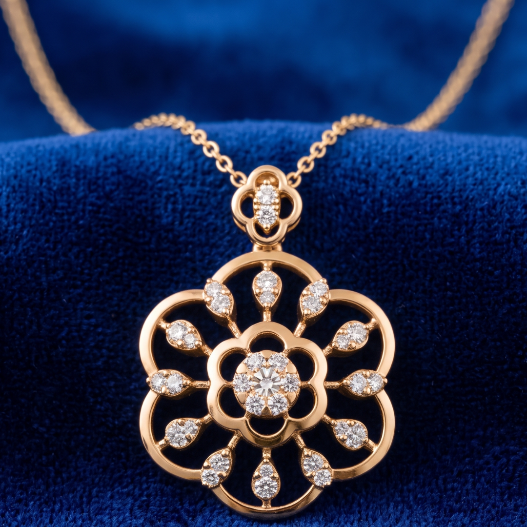 A gold pendant necklace with a floral design set with clear gemstones, displayed on a textured blue velvet surface.