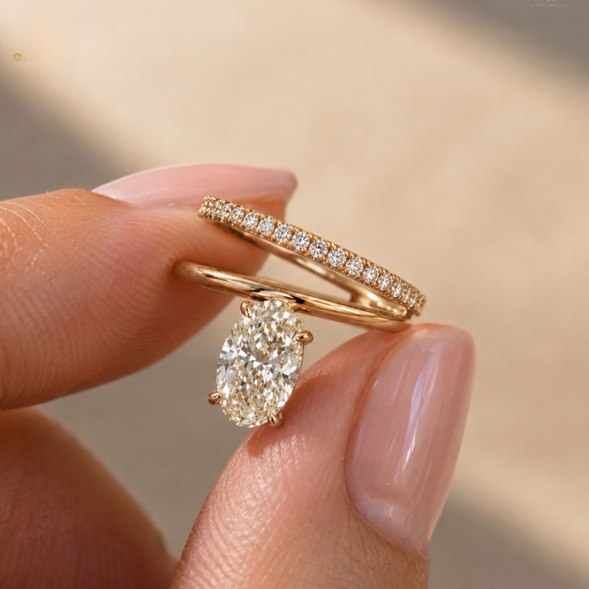 A close-up of a hand holding a rose gold engagement ring with a pear-cut diamond and a matching rose gold wedding band with a row of small diamonds, set against a soft beige background.