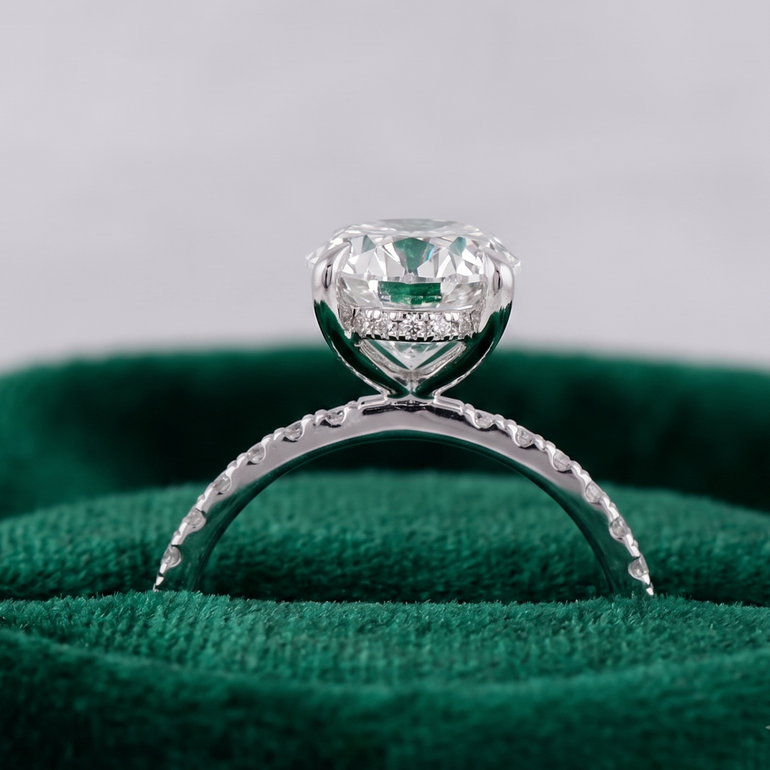 Four-prong oval diamond engagement ring with sparkling shoulders