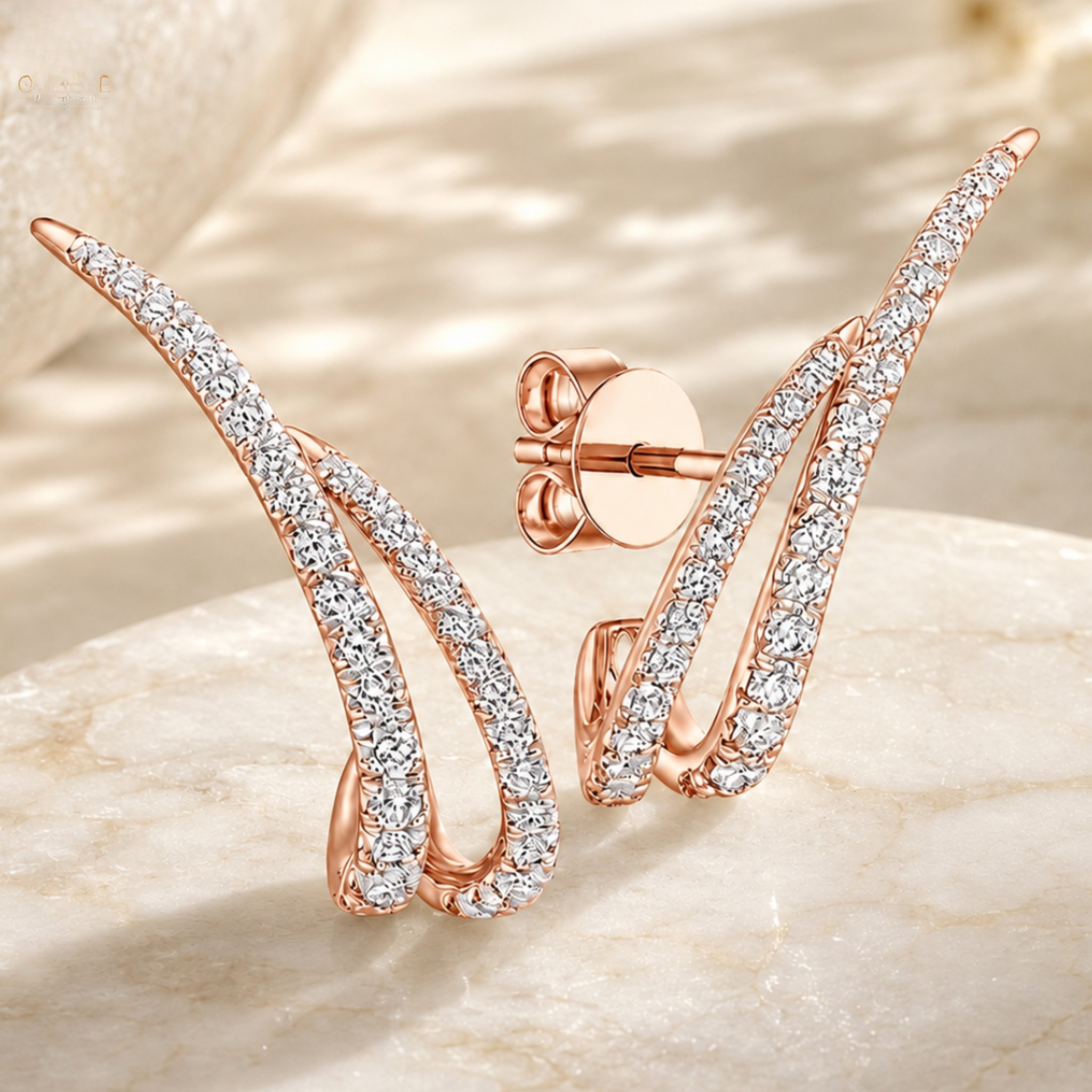 Rose gold wing-shaped stud earrings paved with clear cubic zirconia stones, displayed on a light beige marble surface.