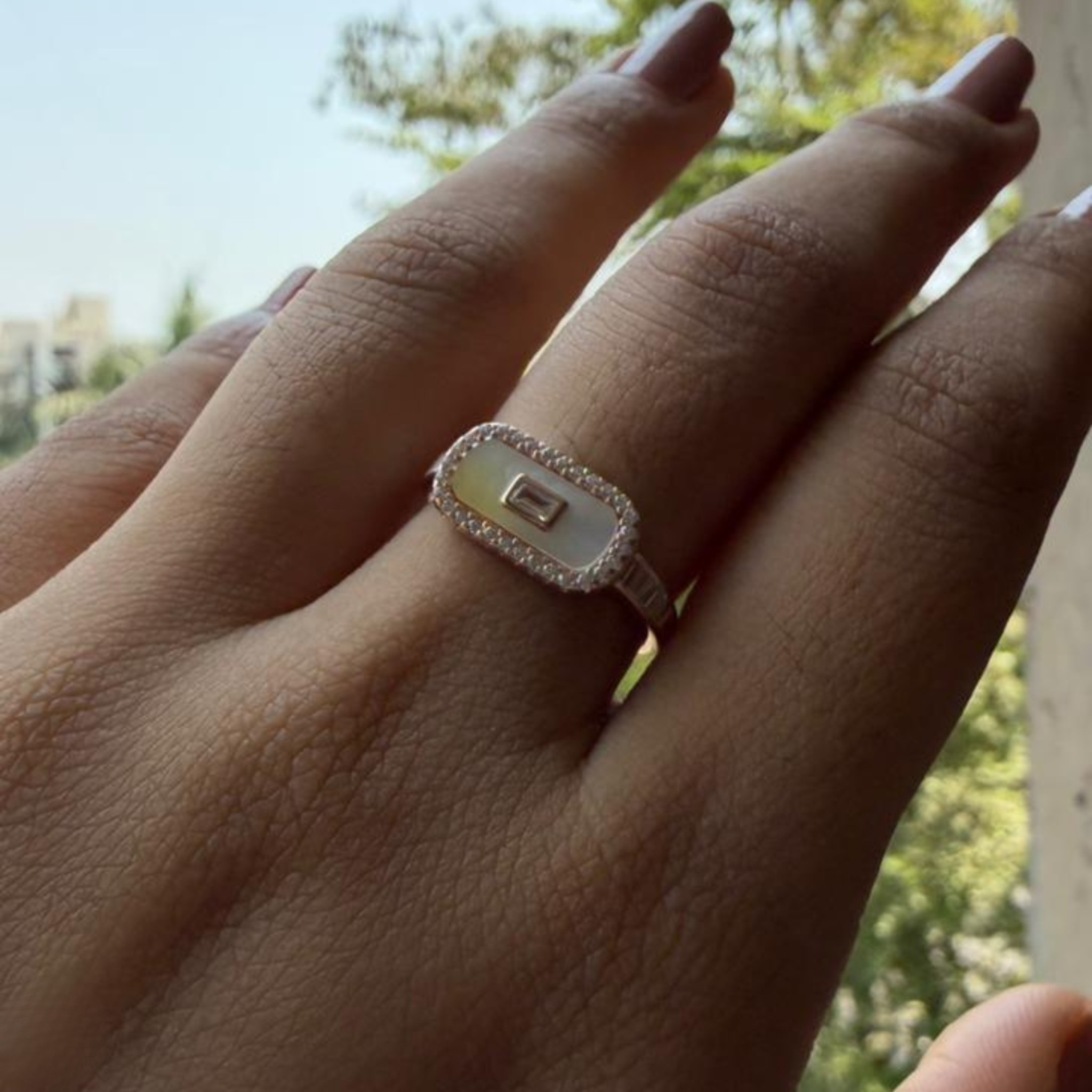 Geometric diamond ring featuring a luminous elongated mother-of-pearl center.