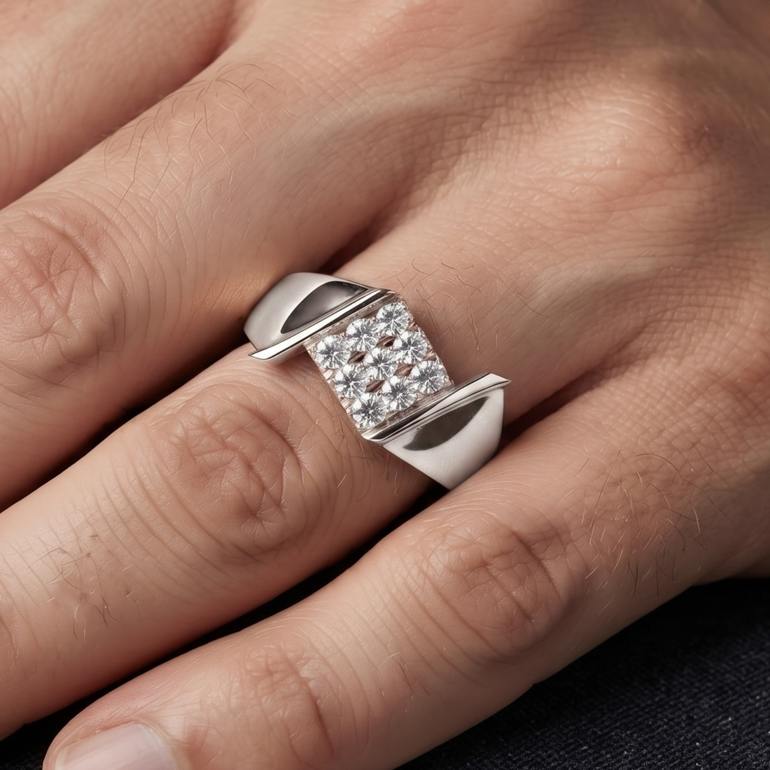 A silver-toned ring with a square pavé diamond center and curved side accents, shown worn on a person's finger.