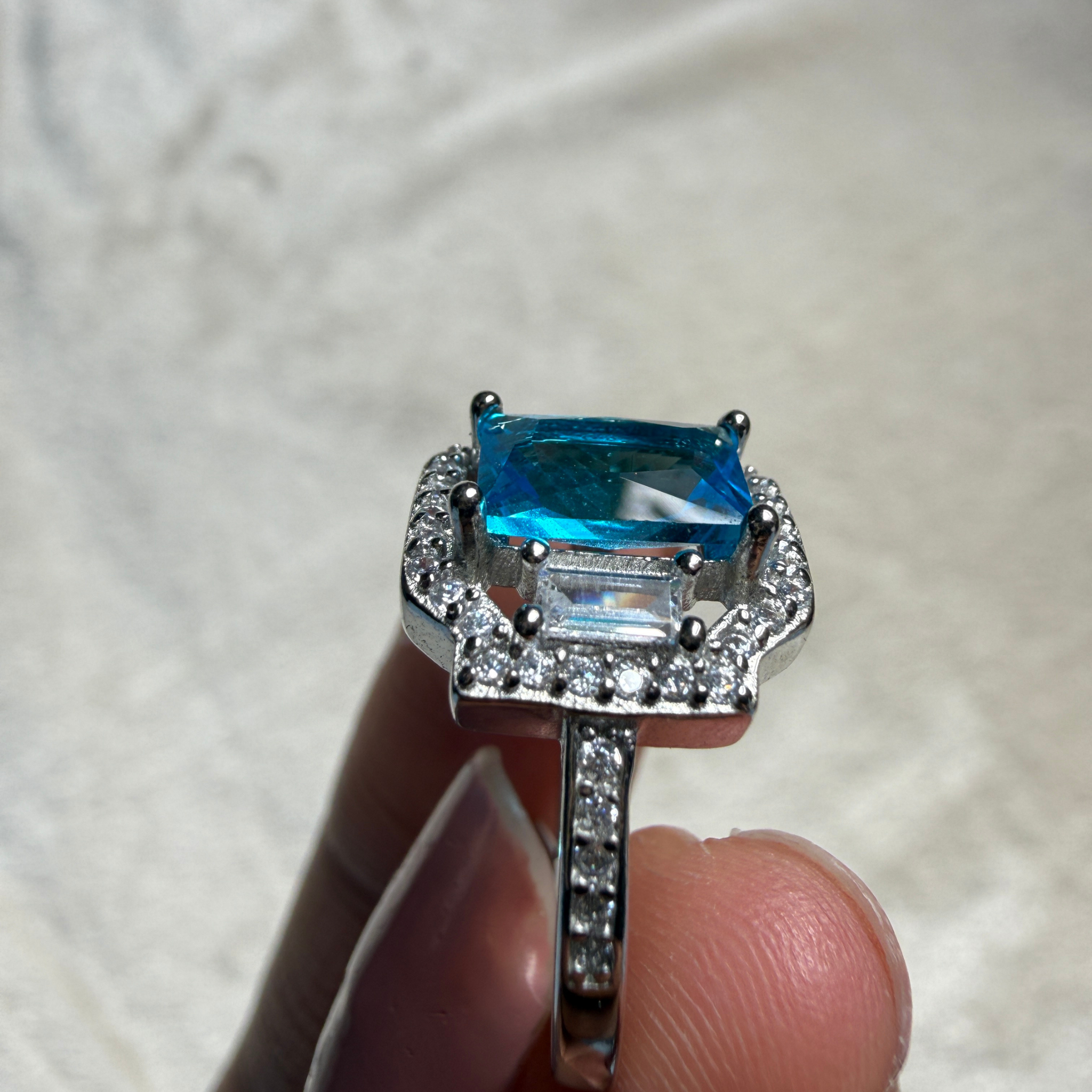 Blue emerald-cut gemstone and lab-grown diamond halo ring by Kiashaa Jewellery.