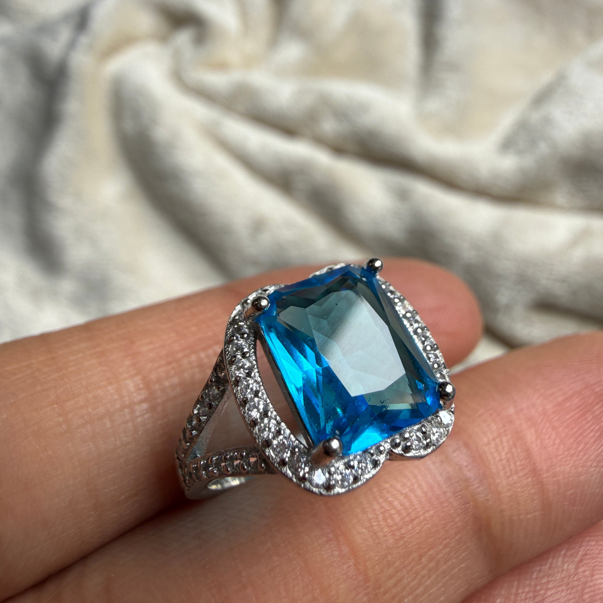 Blue emerald-cut gemstone and lab-grown diamond halo ring by Kiashaa Jewellery.