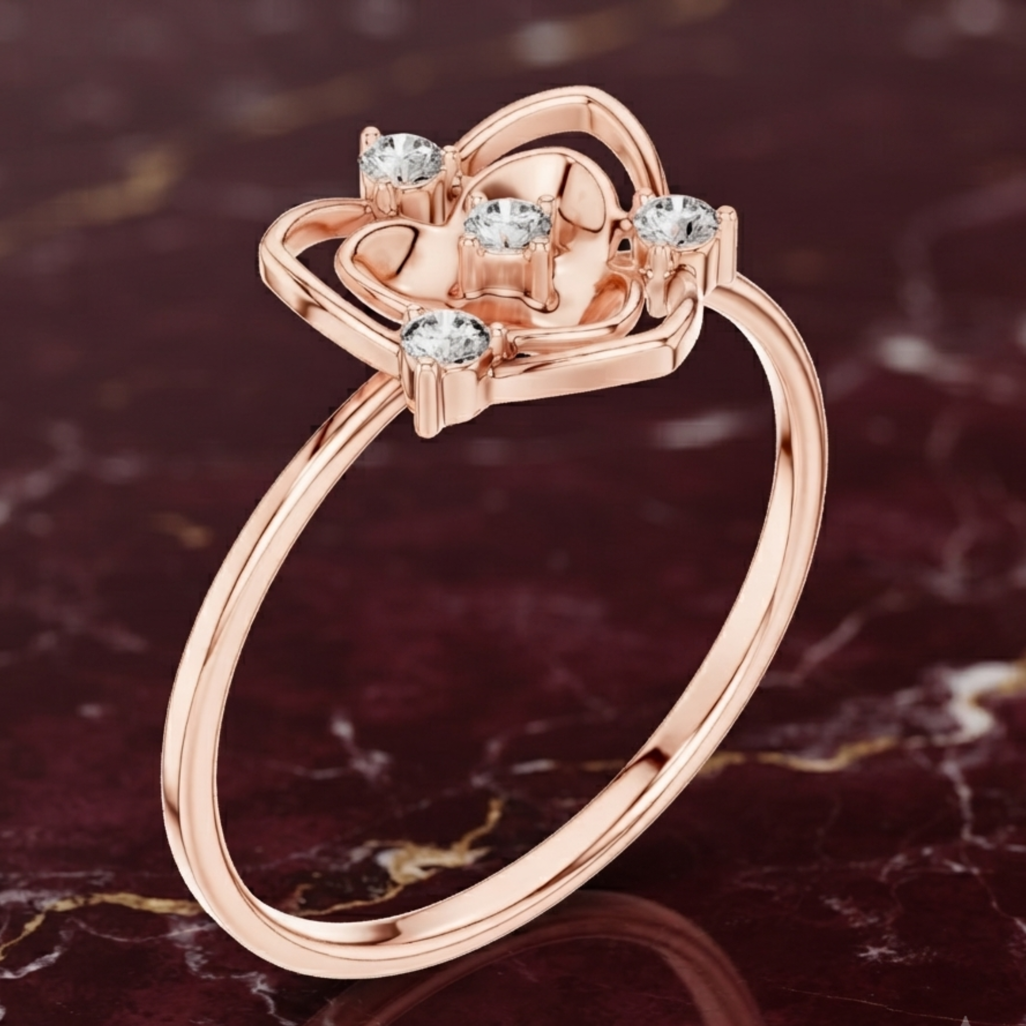 A rose gold ring with a heart-shaped openwork top set with four clear round-cut gemstones, displayed on a dark marbled surface.