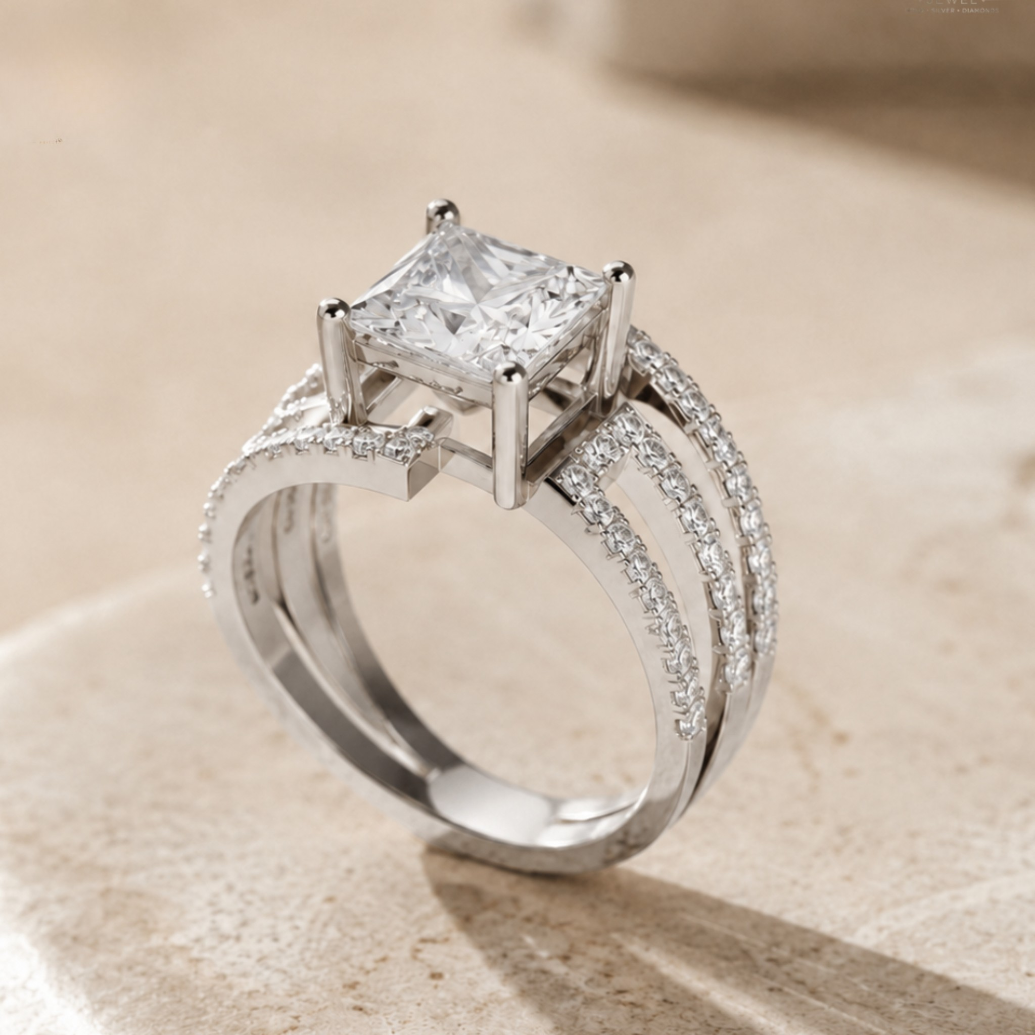A silver-toned diamond ring featuring a princess-cut clear center stone and pavé-set accent diamonds along curved split shanks, photographed on a warm beige stone surface.