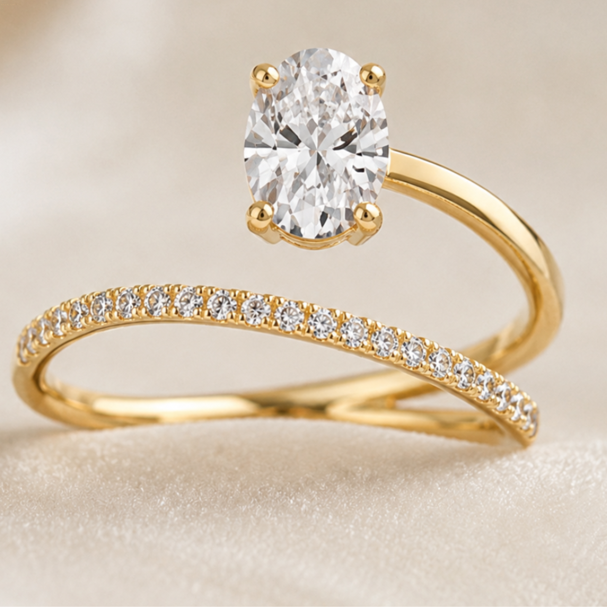 A gold engagement ring with a large oval-cut clear center stone is displayed above a matching gold band set with small round stones, on a soft cream background.