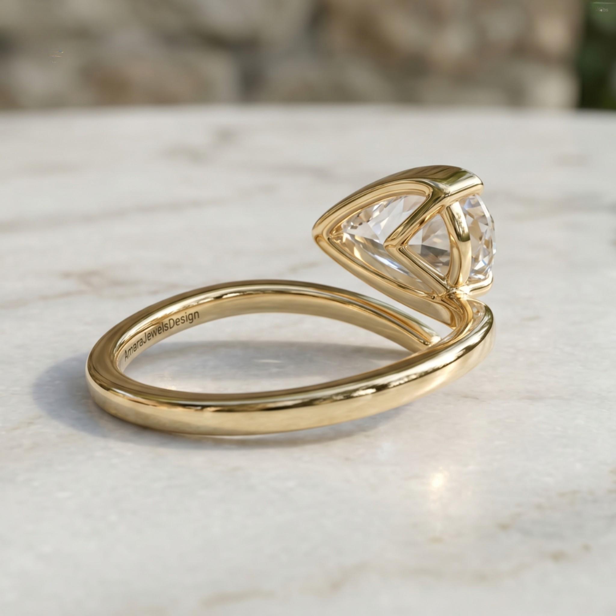 A gold ring with a triangular clear gemstone in a bezel setting, resting on a light marble surface with a blurred stone background.