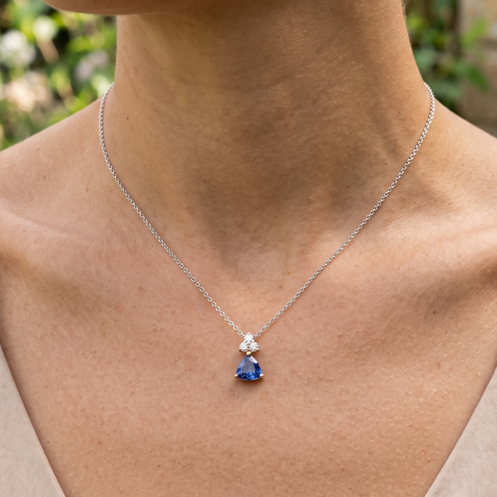 0.96 CTW blue trillion pendant necklace with a 6 mm center stone and three round diamond accents.