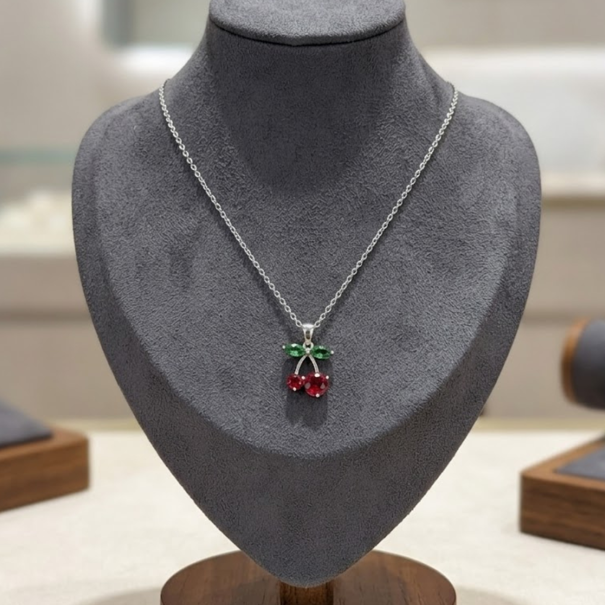 Close-up view of the secure settings on a green diamond and red gemstone necklace.