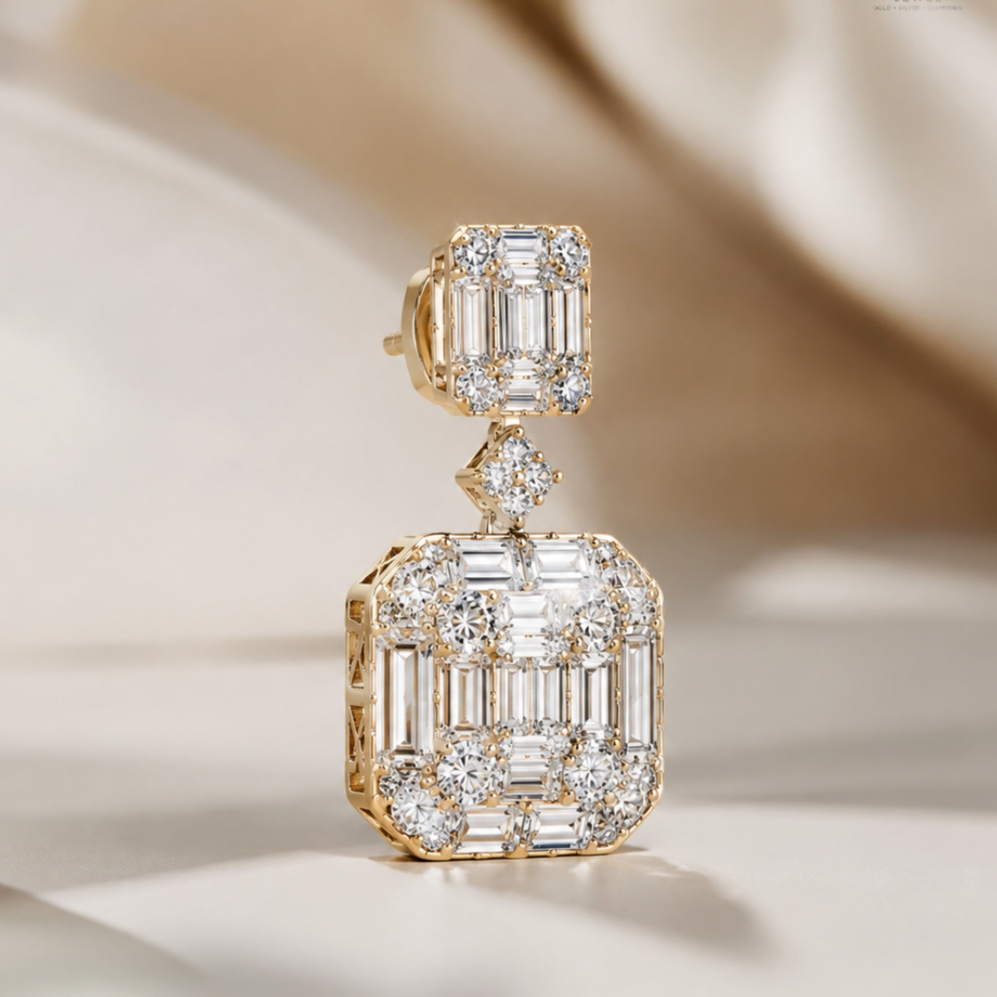 A single gold drop earring with a large square cluster of clear baguette and round-cut stones, photographed on a soft beige draped fabric background.