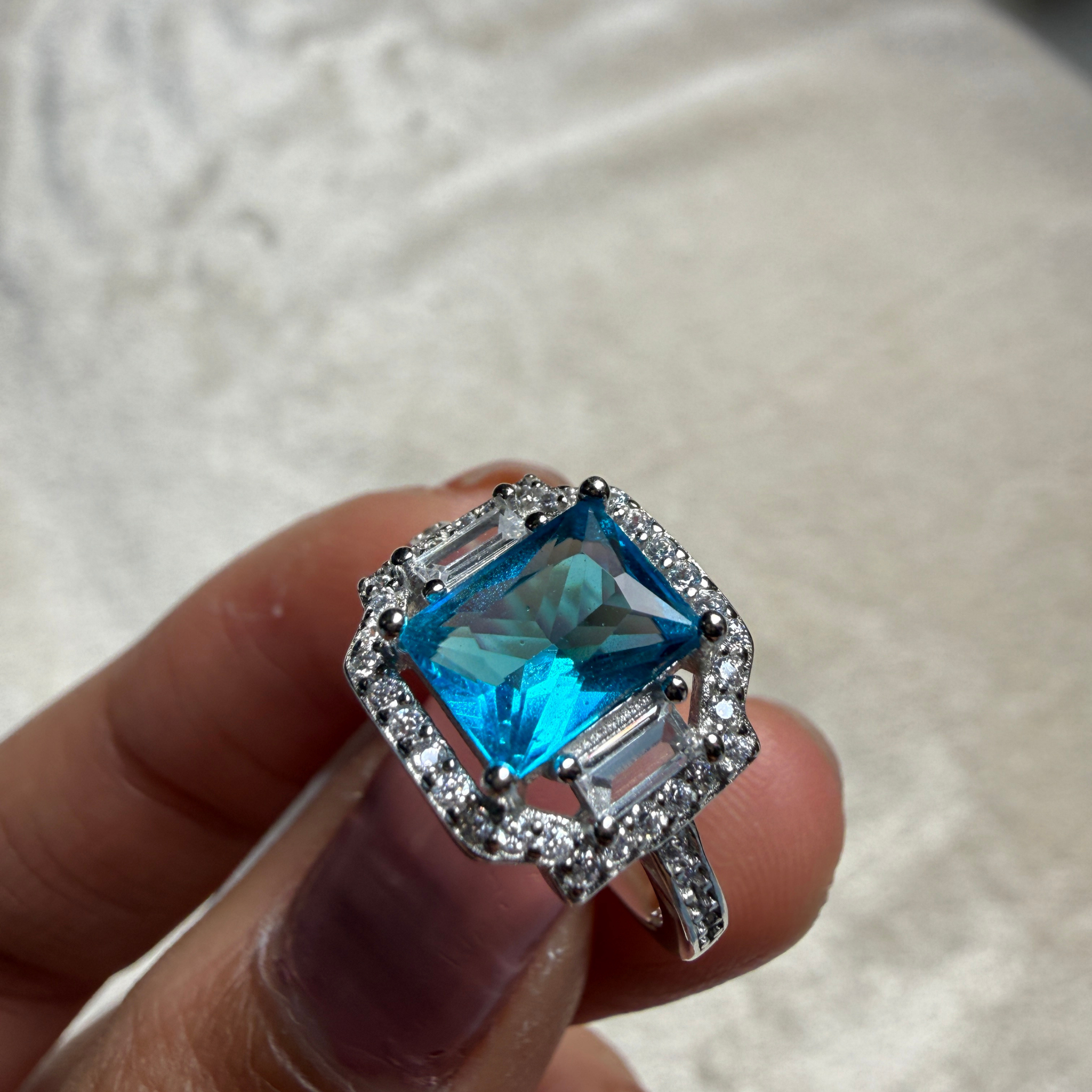 Blue emerald-cut gemstone and lab-grown diamond halo ring by Kiashaa Jewellery.