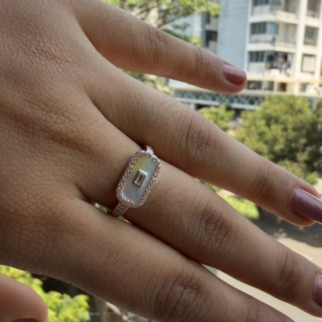 Geometric diamond ring featuring a luminous elongated mother-of-pearl center.