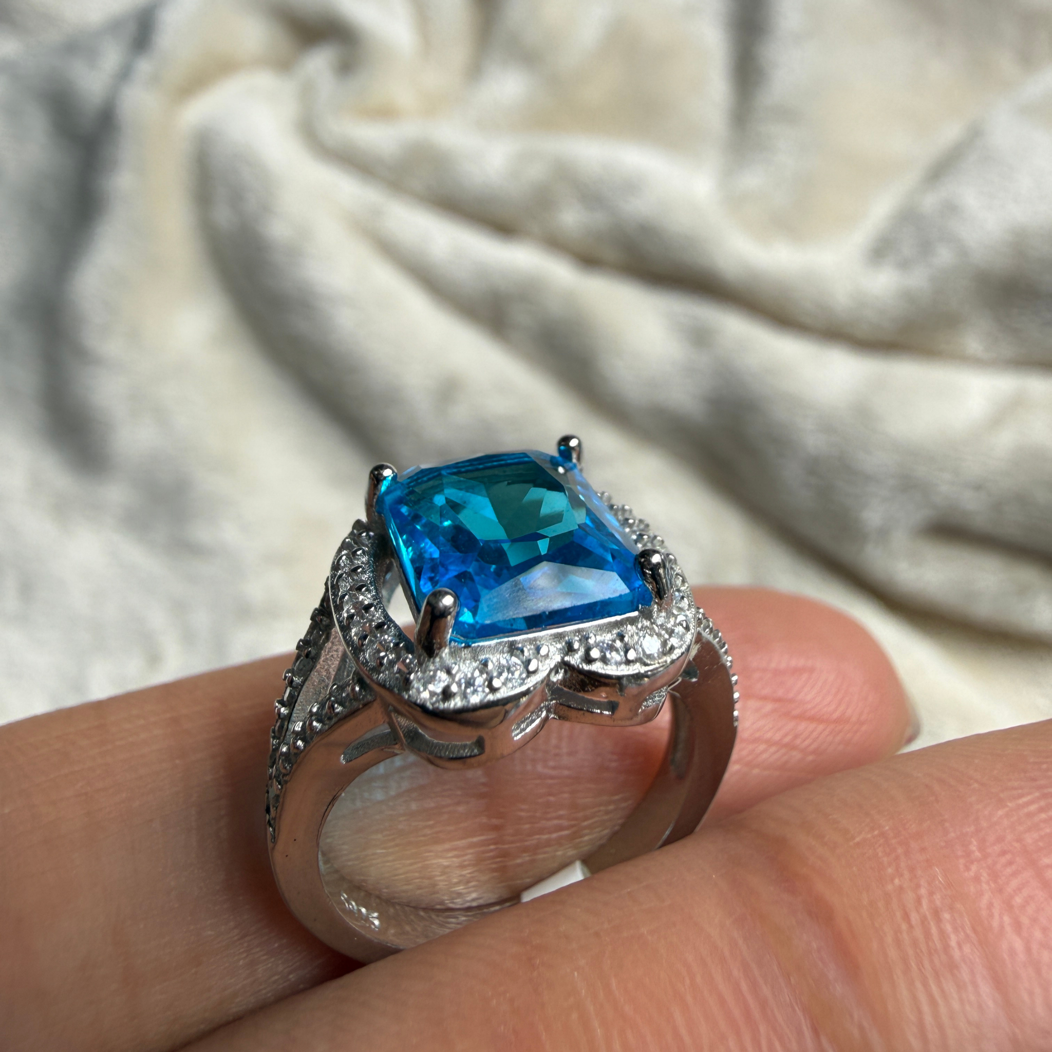 Blue emerald-cut gemstone and lab-grown diamond halo ring by Kiashaa Jewellery.