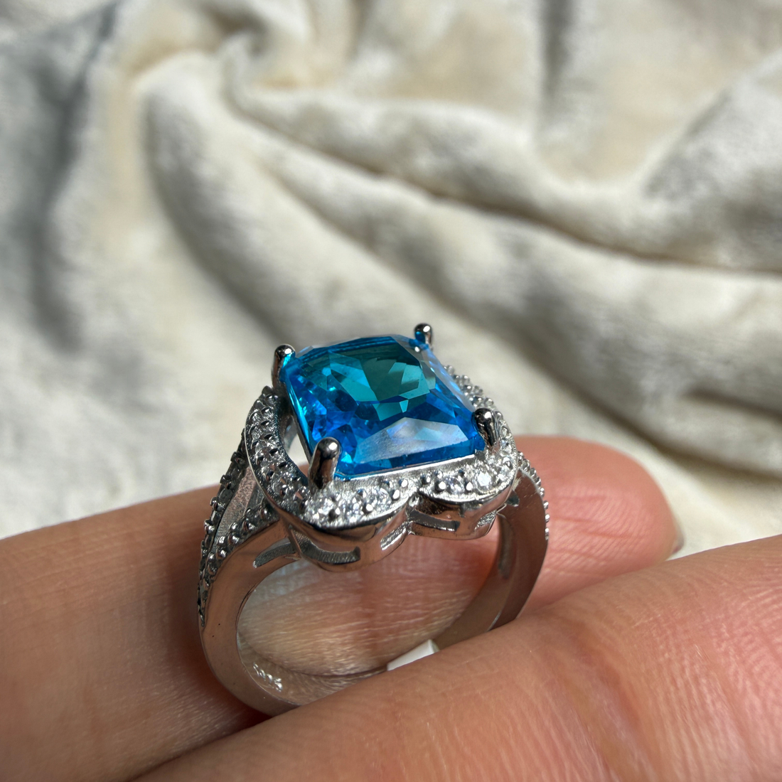 Blue emerald-cut gemstone and lab-grown diamond halo ring by Kiashaa Jewellery.