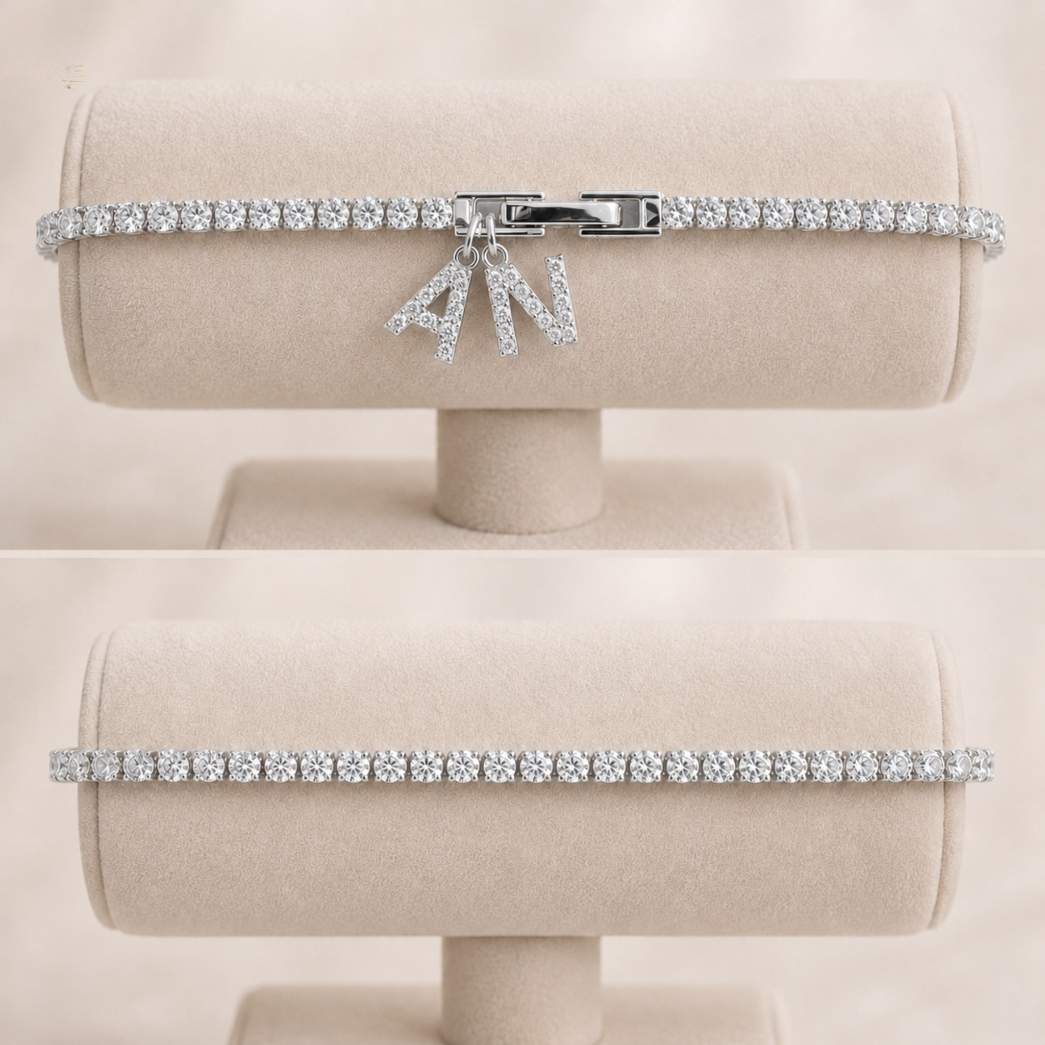 A silver-tone tennis bracelet with a bow charm, set with clear stones, displayed on a beige jewelry stand against a matching beige background.
