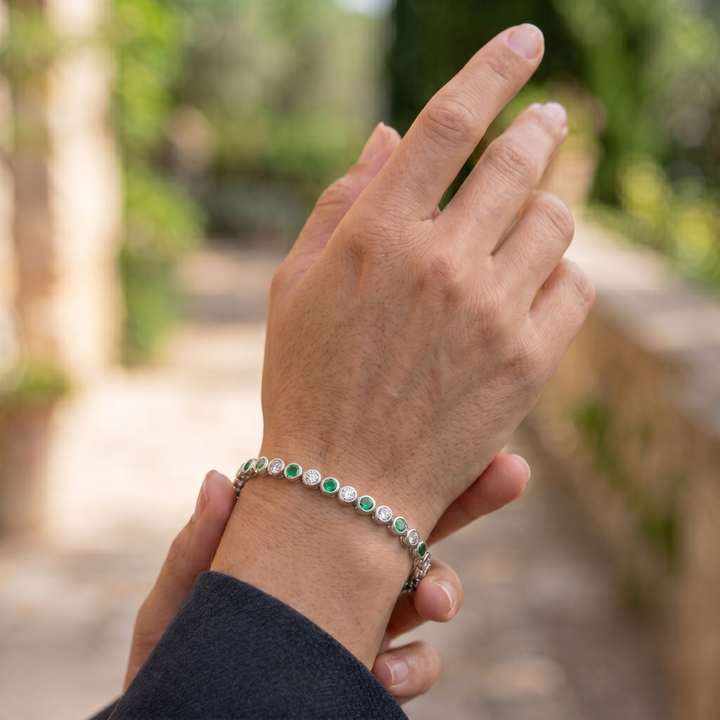Alternating green gemstone and white diamond bracelet with round bezel-set stones.