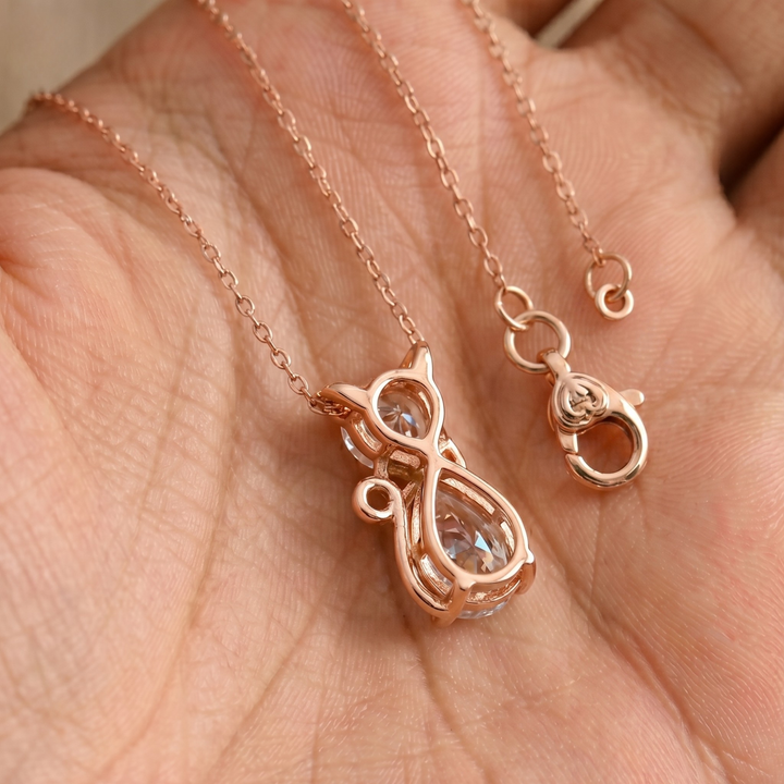 Rose gold necklace with a cat-shaped pendant and matching clasp, displayed on a person's palm.