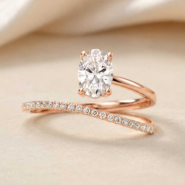 A rose gold engagement ring with a large oval-cut center stone and a matching rose gold band set with small pavé diamonds, displayed on a soft beige fabric background.