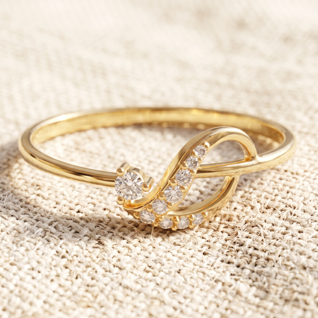 A gold ring with a stylized infinity symbol design, featuring a round clear gemstone and a row of small clear stones, resting on a textured beige fabric background.