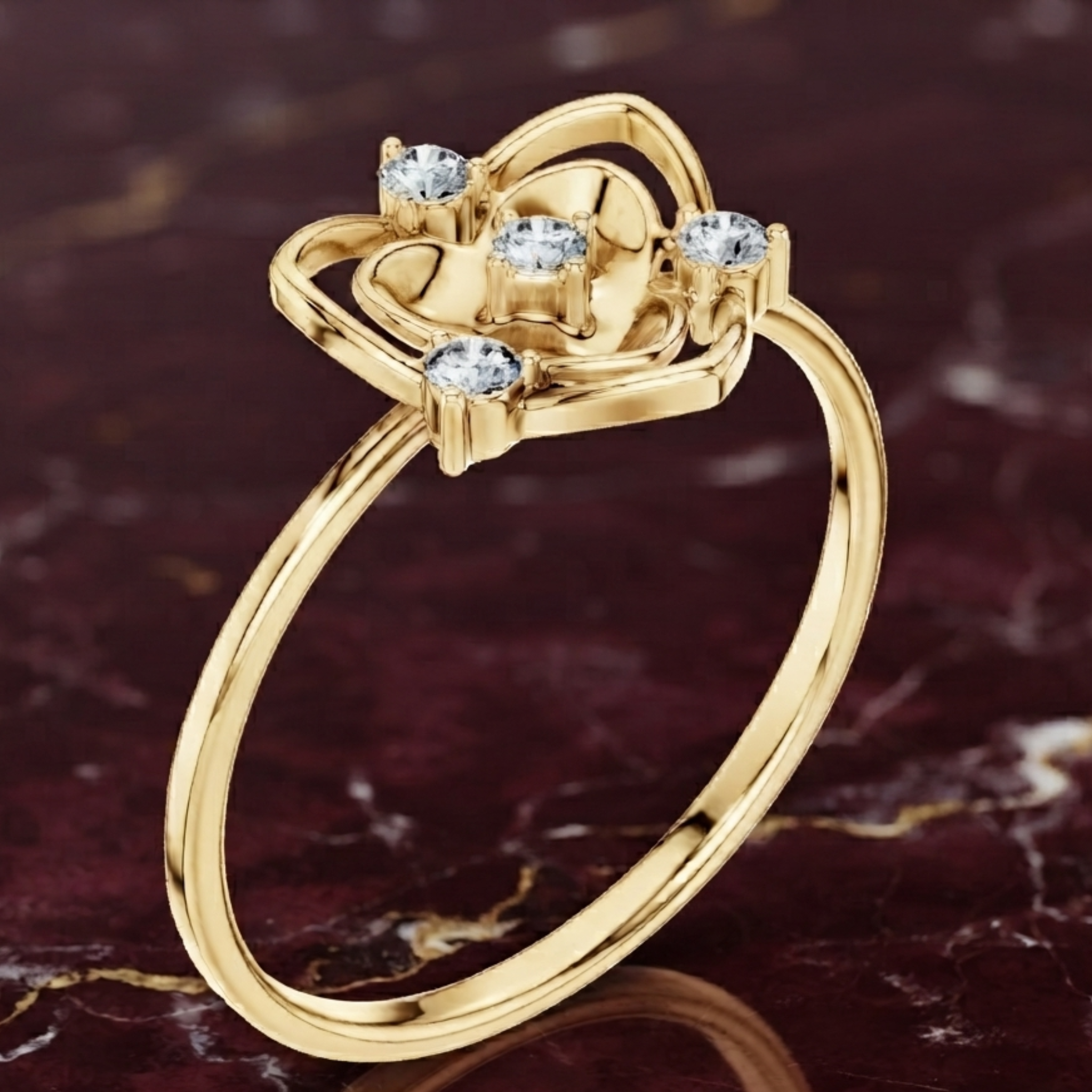 A yellow gold ring with a decorative openwork top set with four clear round gemstones, displayed on a dark marbled surface.