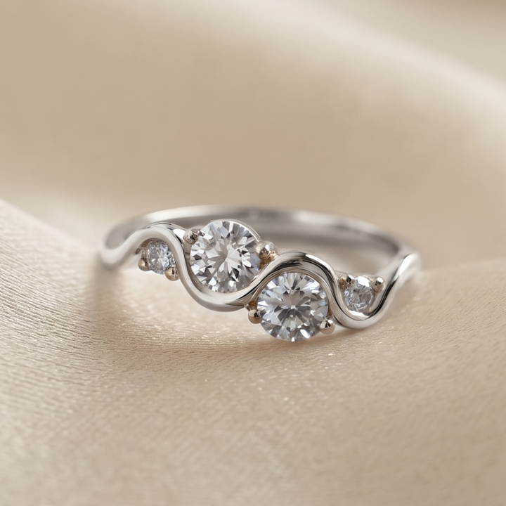 A gold ring with three round-cut clear gemstones set on a person's finger, shown in a close-up shot.