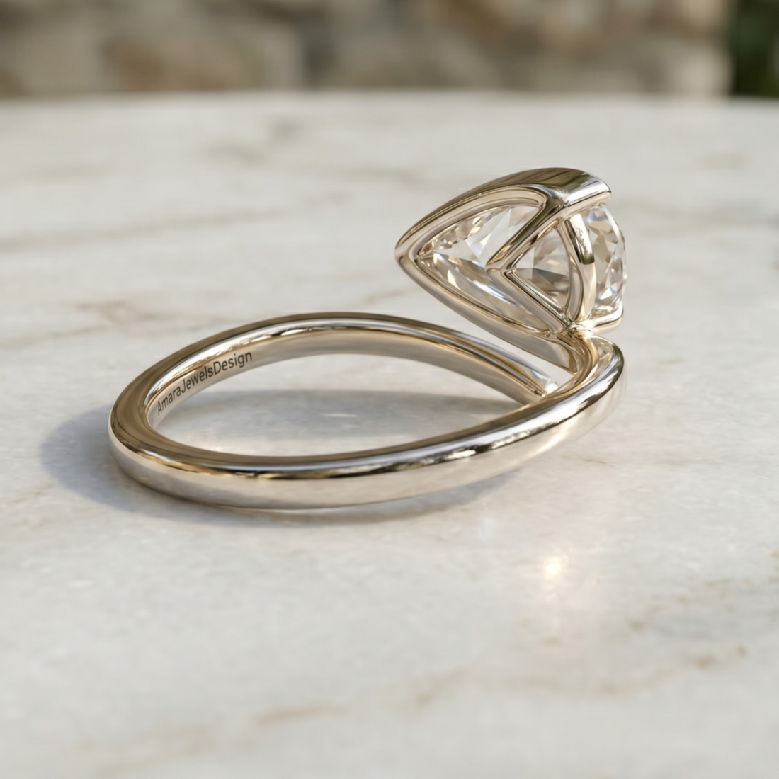 A silver-toned split ring featuring a triangular prong setting with a clear gemstone, resting on a light marble surface.