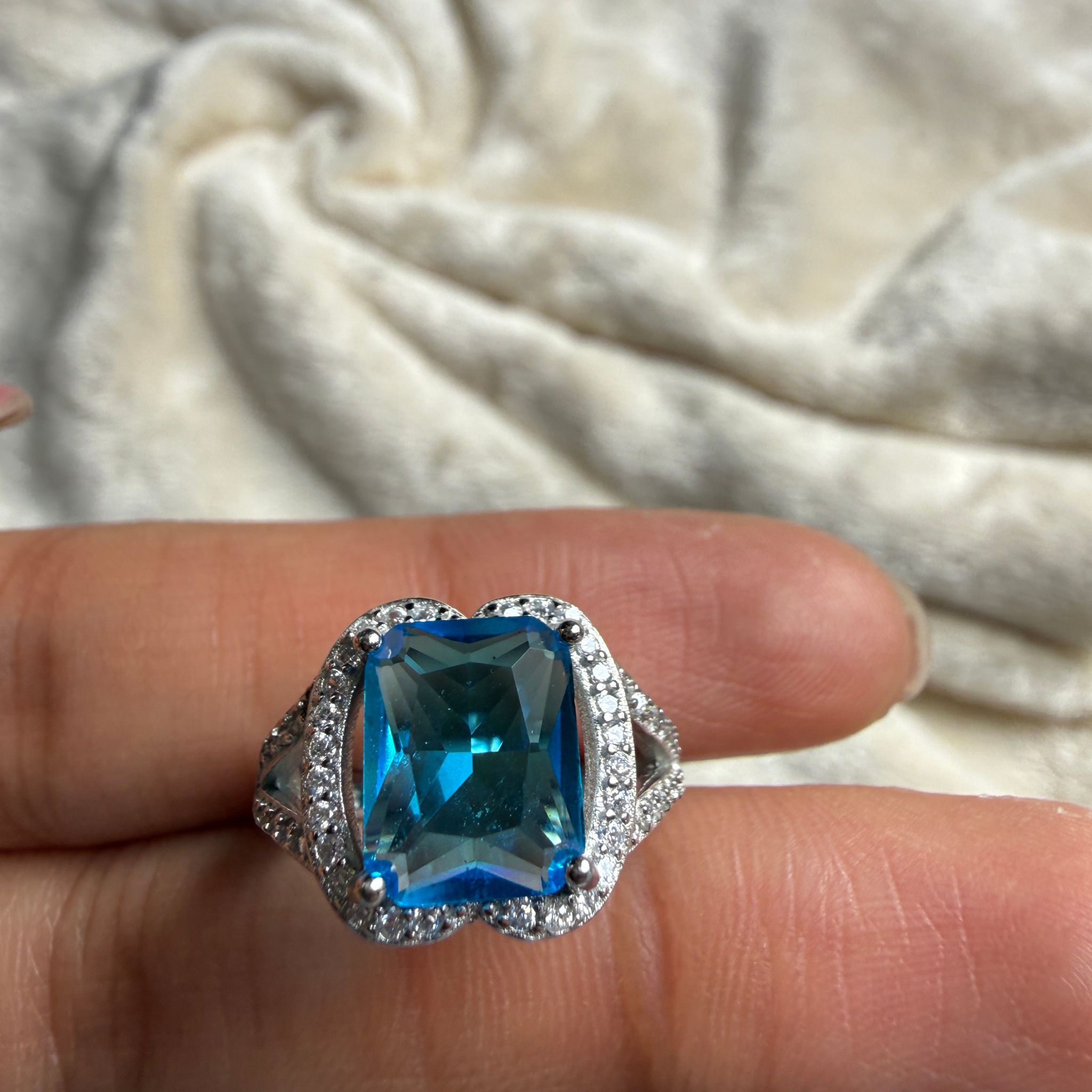 Blue emerald-cut gemstone and lab-grown diamond halo ring by Kiashaa Jewellery.