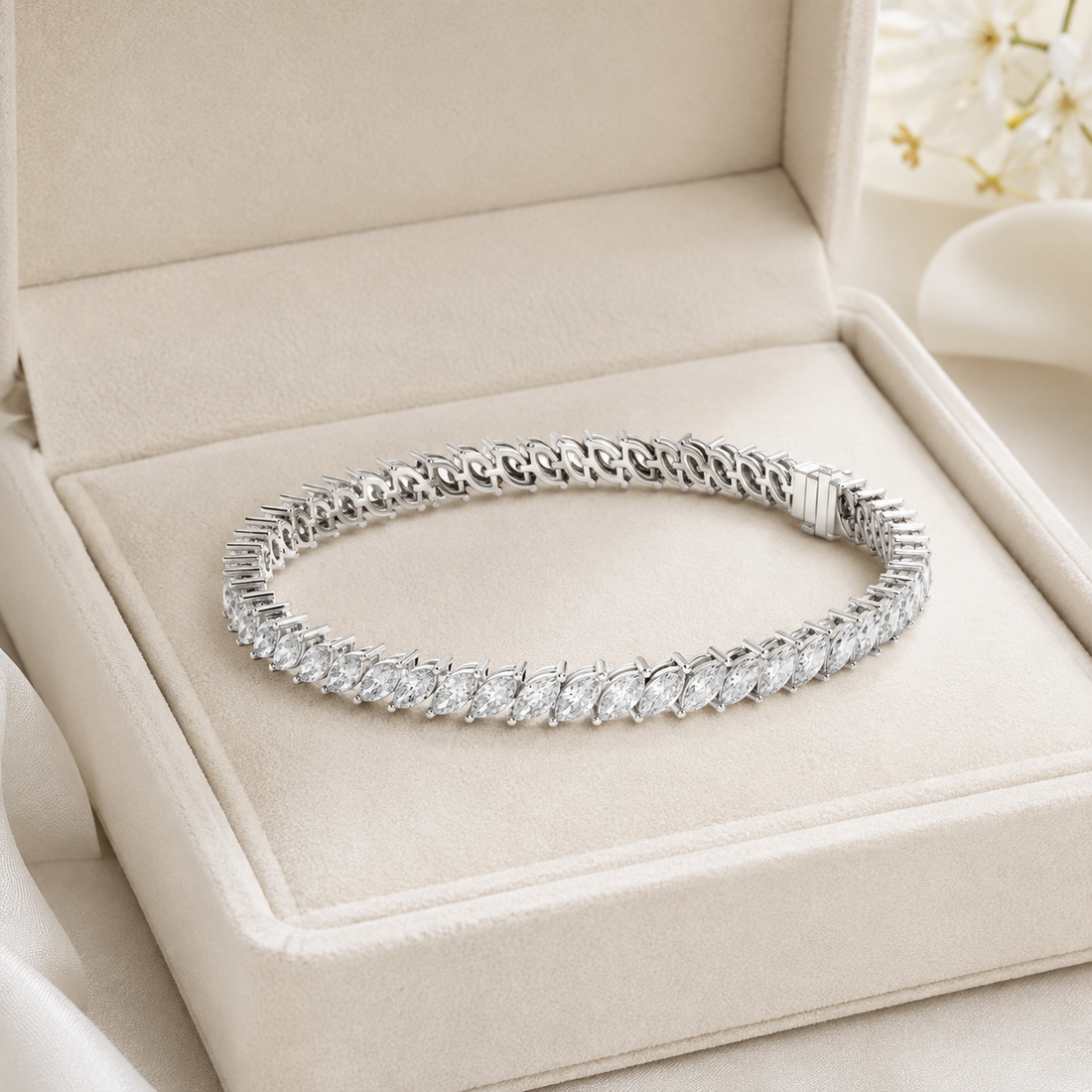 A silver tennis bracelet with a row of clear round-cut stones, displayed inside an open beige jewelry box.