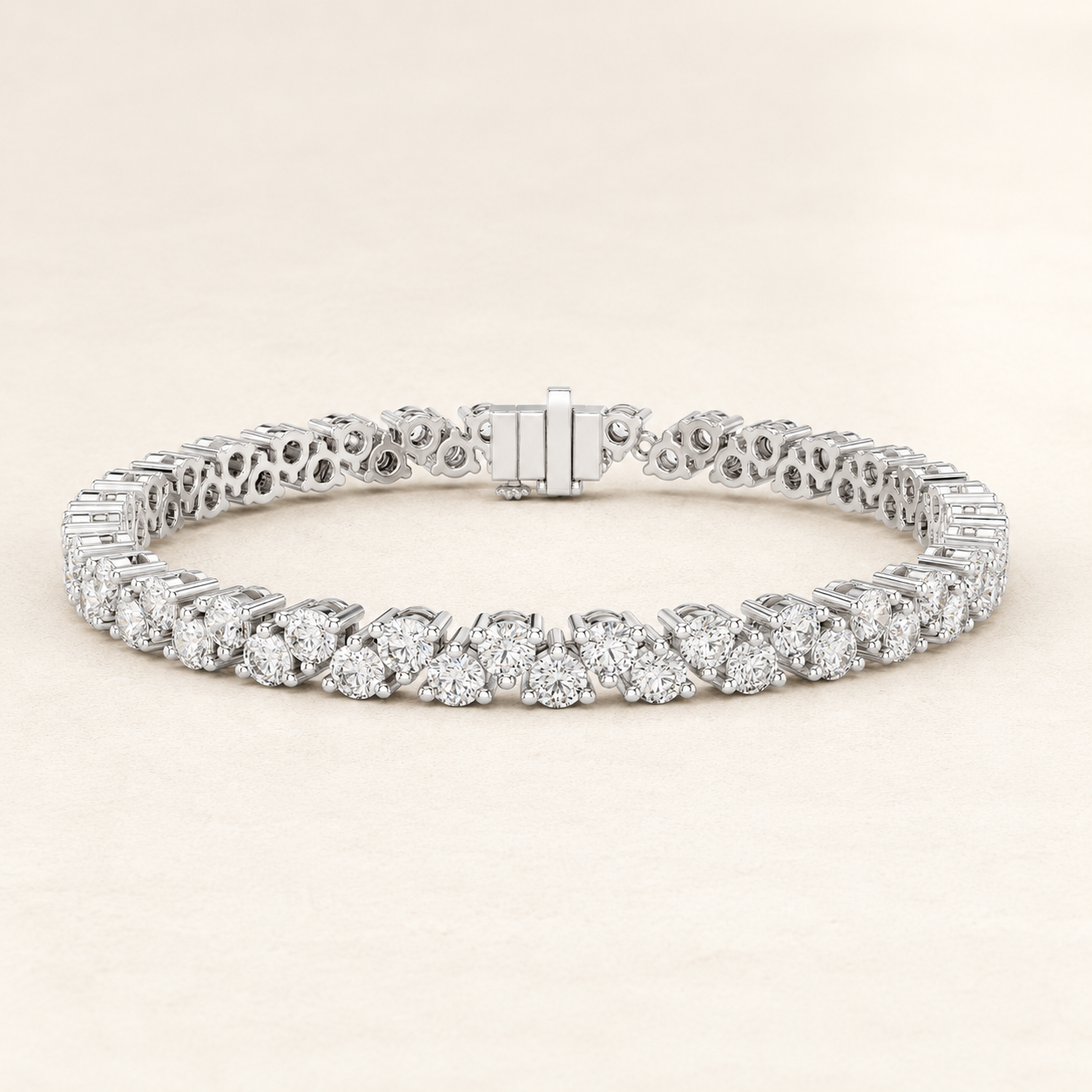 A diamond tennis bracelet in a silver-toned metal, featuring a continuous row of round-cut diamonds and an openwork filigree pattern on the back, displayed on a light beige background.