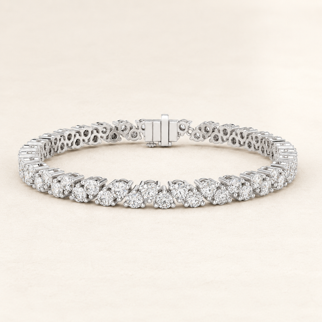 A diamond tennis bracelet in a silver-toned metal, featuring a continuous row of round-cut diamonds and an openwork filigree pattern on the back, displayed on a light beige background.