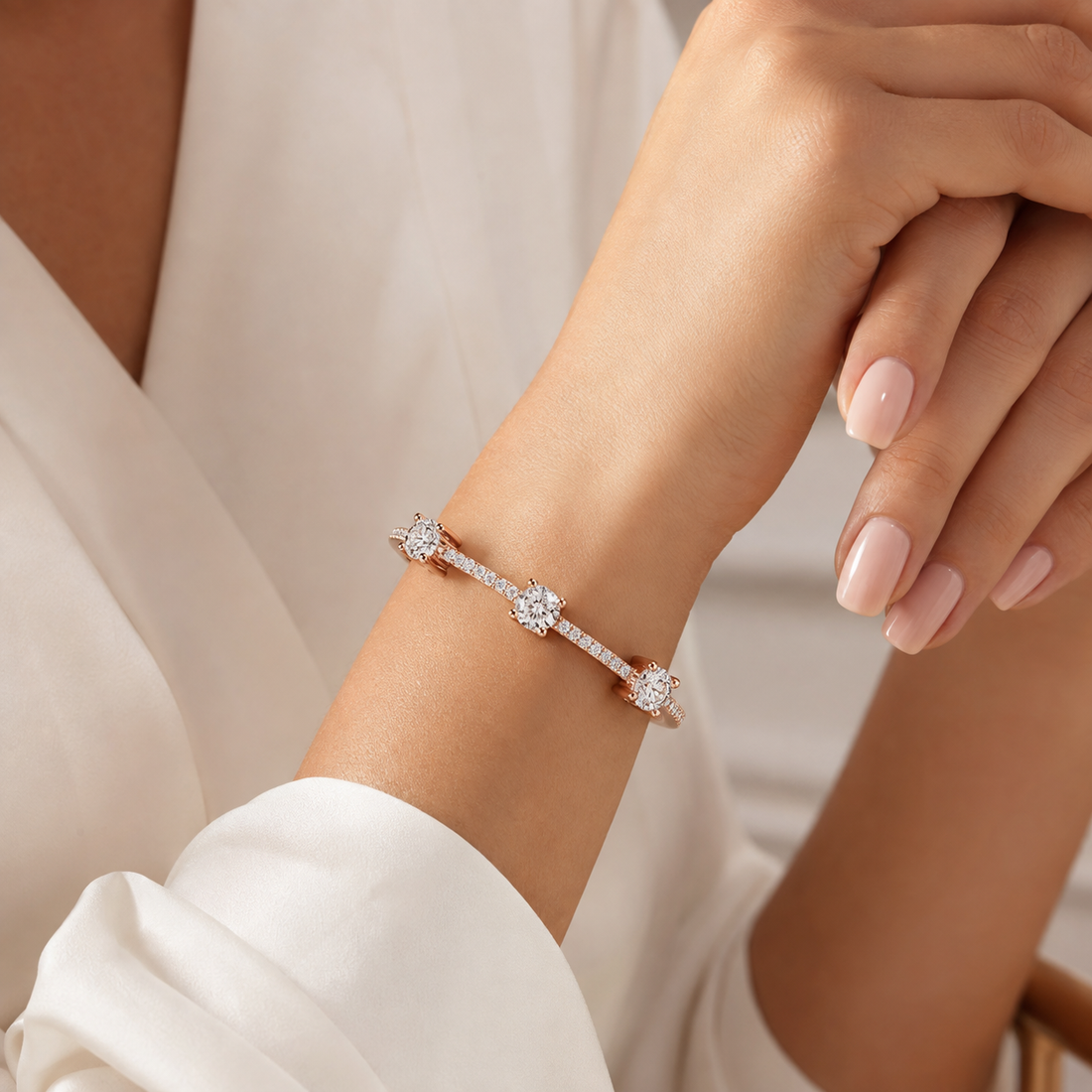 A close-up lifestyle shot of a delicate bracelet worn on a woman's wrist. The bracelet features three small star-shaped clusters of clear pavé-set gemstones on a thin silver-toned band.