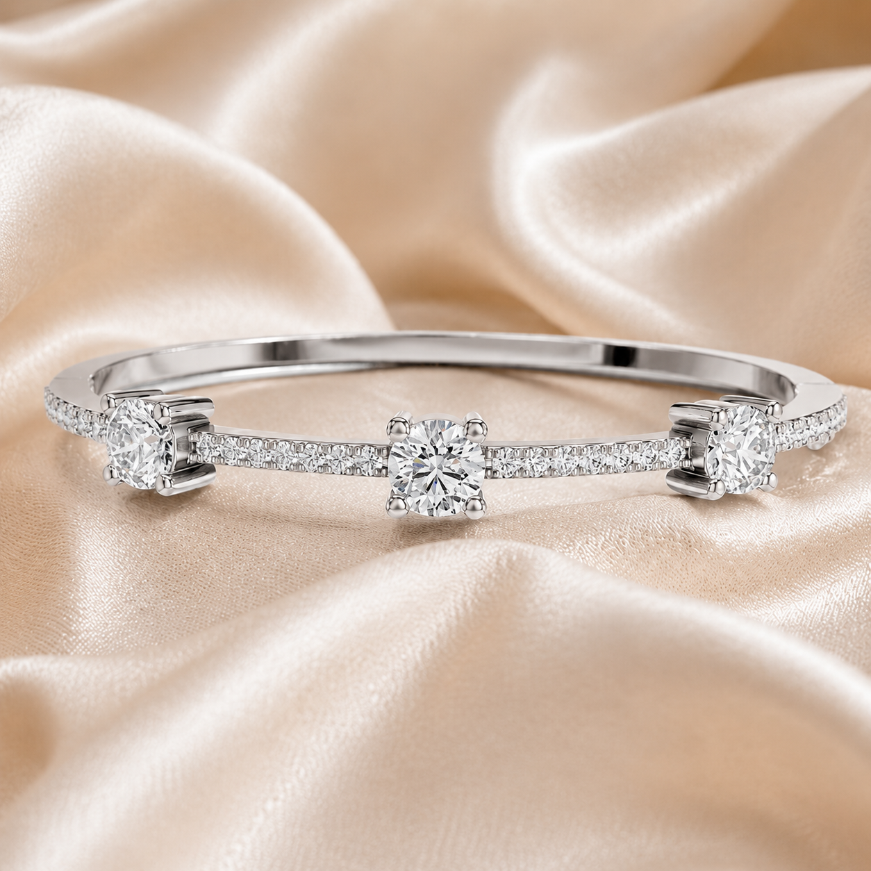A silver-toned diamond band ring with three round-cut center stones and pavé-set side stones, displayed on draped champagne satin fabric.